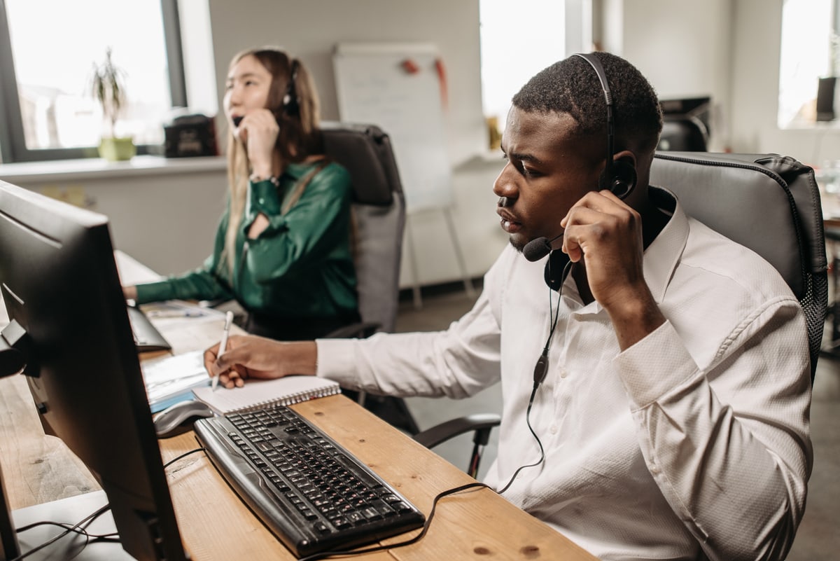 man sitting at a desk taking calls with a headset
