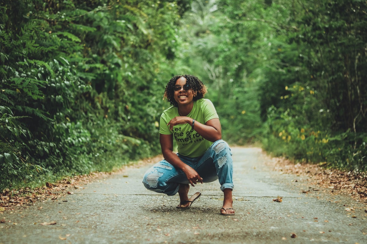 woman squatting on path in the woods